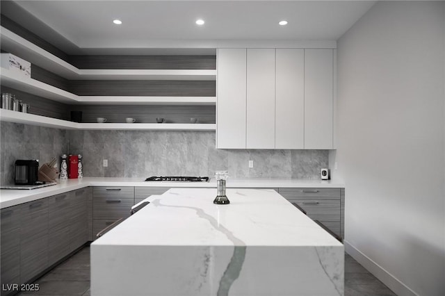 kitchen with open shelves, modern cabinets, a center island, and light stone countertops