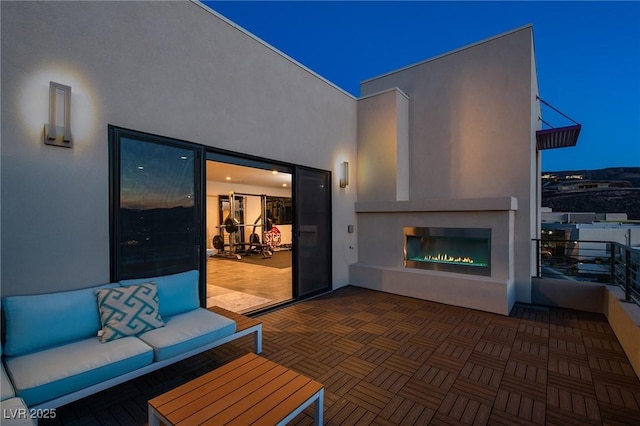 view of patio featuring a balcony and an outdoor living space with a fireplace