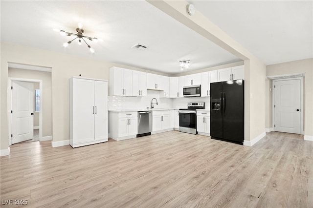 kitchen featuring white cabinets, light wood-style floors, appliances with stainless steel finishes, and light countertops