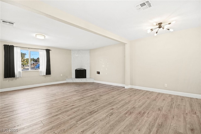 unfurnished living room featuring light wood-type flooring, a brick fireplace, and visible vents