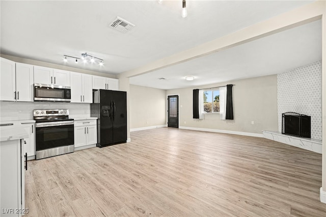 kitchen featuring appliances with stainless steel finishes, open floor plan, light countertops, and white cabinetry