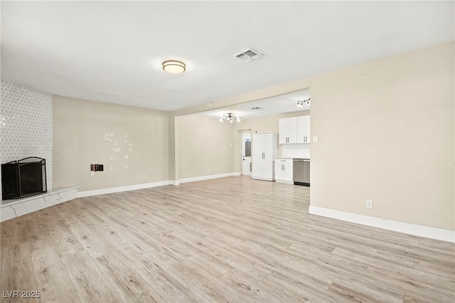 unfurnished living room with a tile fireplace, baseboards, visible vents, and light wood finished floors