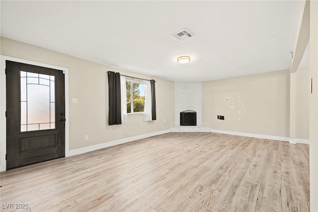 unfurnished living room featuring light wood-style floors, a brick fireplace, visible vents, and baseboards