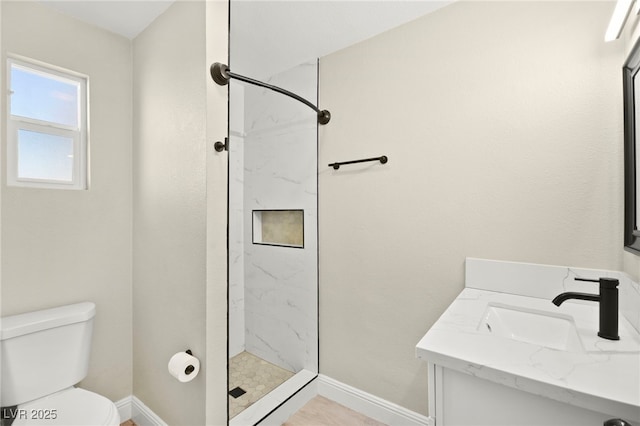 bathroom with toilet, a stall shower, baseboards, and vanity