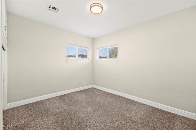 empty room with carpet floors, visible vents, and baseboards