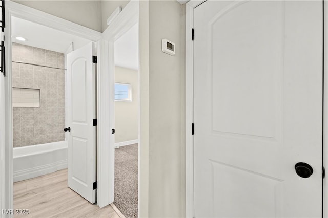 hall with light wood-type flooring and baseboards