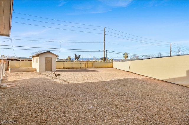 view of yard featuring a fenced backyard, a storage unit, and an outdoor structure