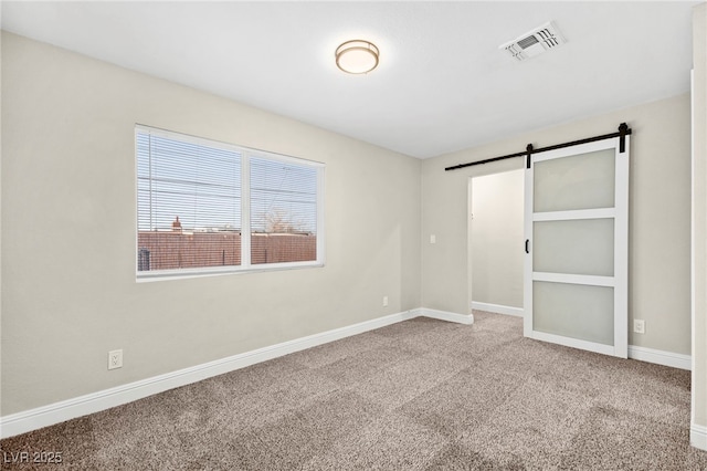 unfurnished bedroom featuring baseboards, a barn door, visible vents, and carpet flooring