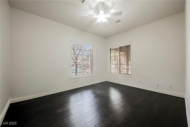 empty room with baseboards, visible vents, dark wood finished floors, and a ceiling fan