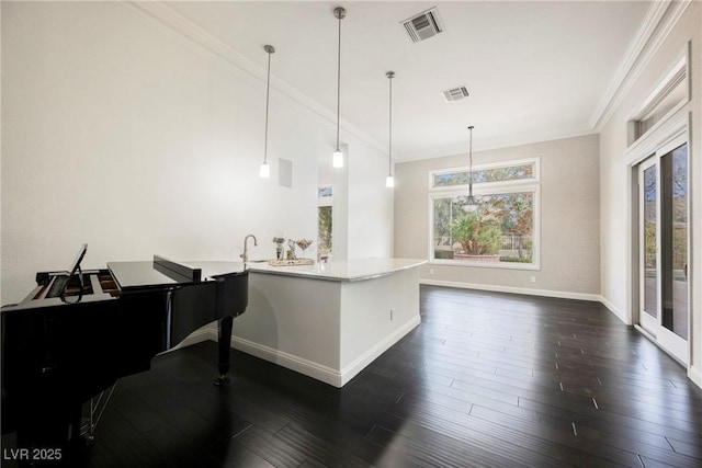 kitchen with dark wood finished floors, visible vents, crown molding, and decorative light fixtures