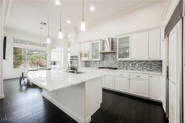 kitchen with light stone counters, wall chimney range hood, glass insert cabinets, and white cabinets