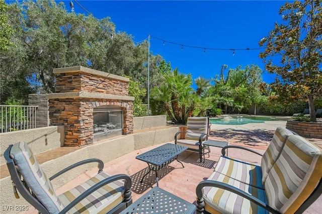 view of patio / terrace with fence, an outdoor stone fireplace, and an outdoor pool