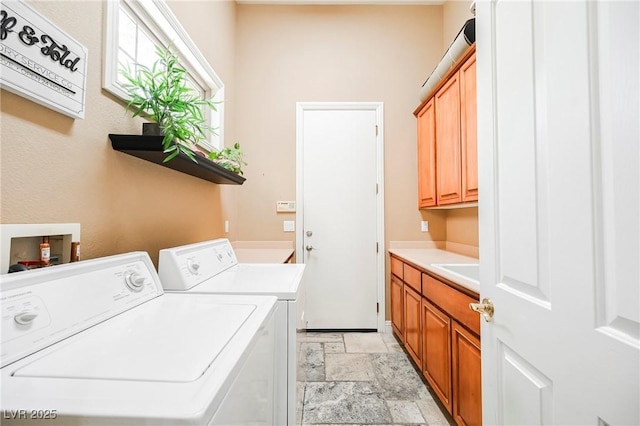 clothes washing area featuring washing machine and clothes dryer, cabinet space, and stone tile floors