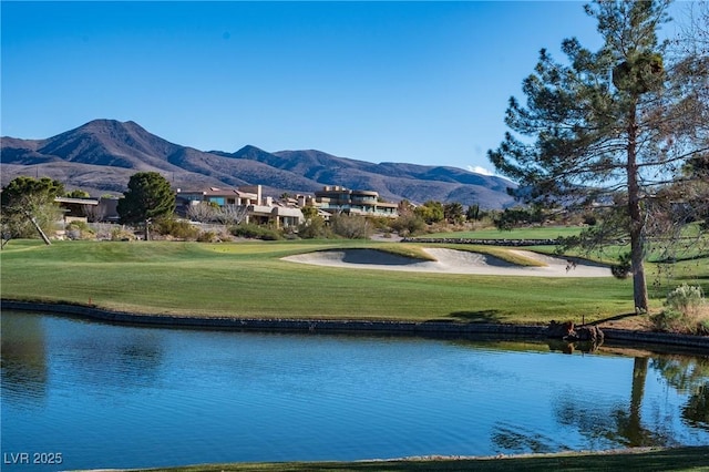 view of home's community with a lawn, golf course view, and a water and mountain view