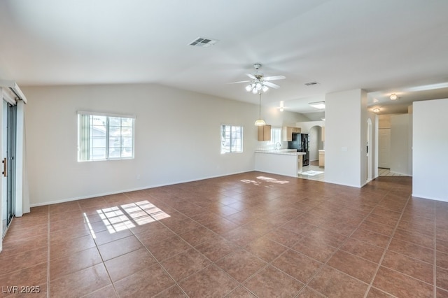 unfurnished living room featuring arched walkways, visible vents, ceiling fan, and dark tile patterned floors