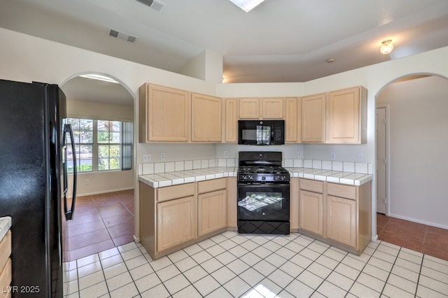 kitchen featuring visible vents, tile countertops, black appliances, and light tile patterned floors