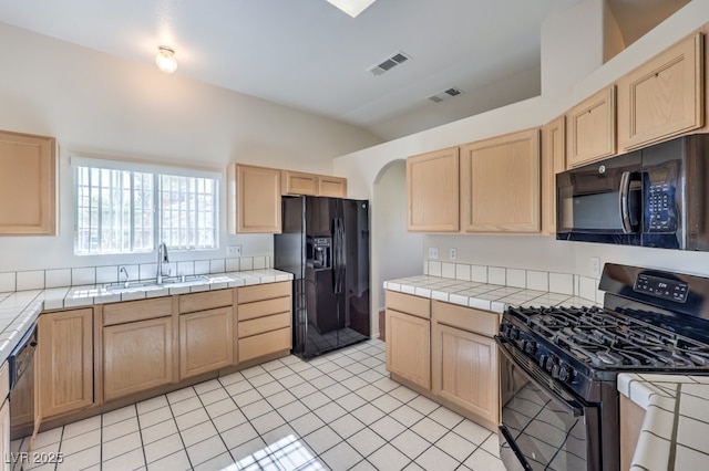 kitchen featuring tile countertops, black appliances, a sink, and visible vents