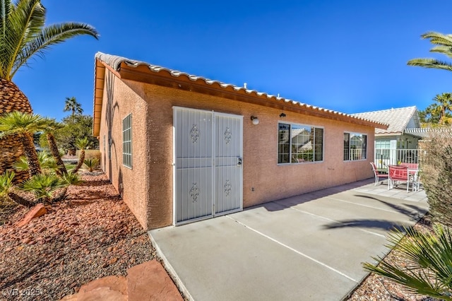 rear view of house with a patio area, fence, and stucco siding