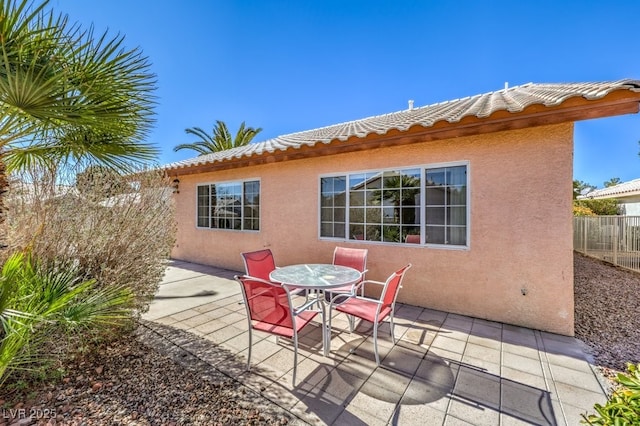 rear view of house featuring outdoor dining area, a patio, a tiled roof, and stucco siding