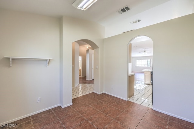 spare room with dark tile patterned floors, visible vents, and arched walkways