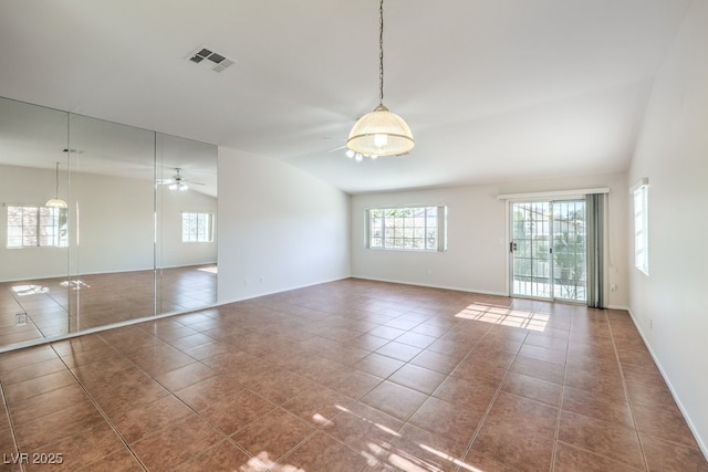 empty room featuring lofted ceiling, dark tile patterned floors, visible vents, and ceiling fan