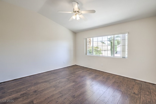 empty room featuring lofted ceiling, dark wood finished floors, a ceiling fan, and baseboards