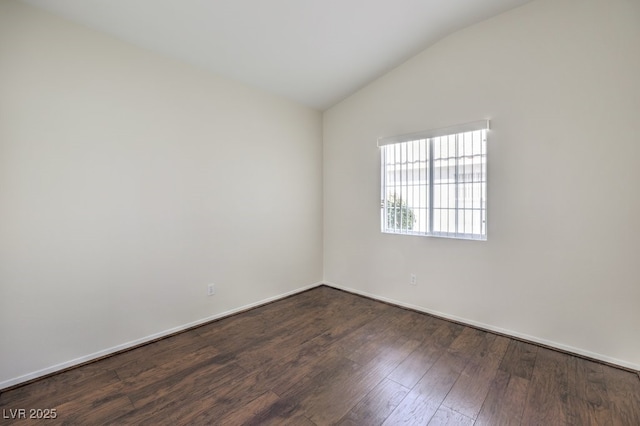 empty room featuring dark wood-style floors, lofted ceiling, and baseboards