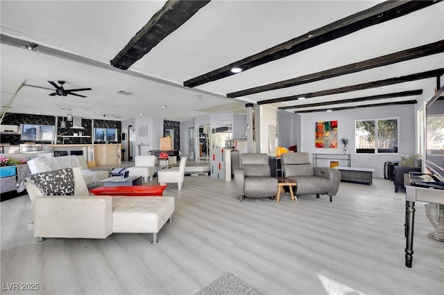 living area with beam ceiling, ceiling fan, and light wood finished floors