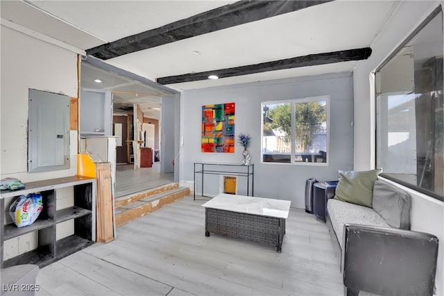 living room featuring light wood finished floors, beamed ceiling, and electric panel