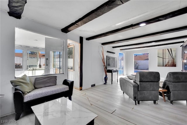 living room featuring light wood-style floors, baseboards, and beam ceiling