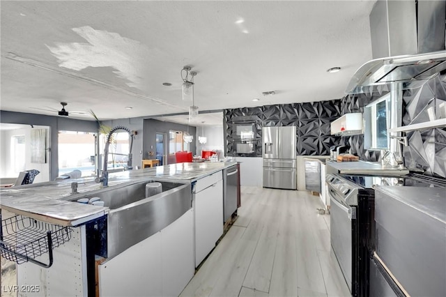 kitchen with appliances with stainless steel finishes, light wood-style floors, white cabinetry, a sink, and ceiling fan