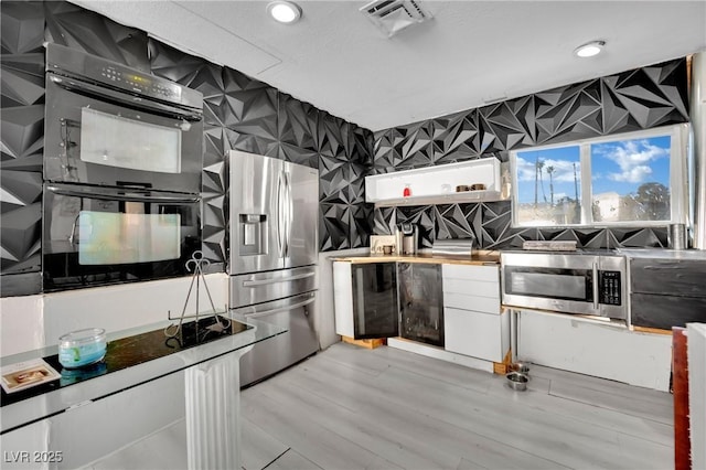 kitchen with stainless steel appliances, recessed lighting, visible vents, light wood-style floors, and wallpapered walls