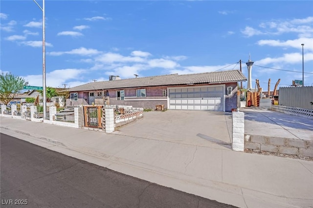 ranch-style home featuring driveway, a fenced front yard, a garage, and a tiled roof