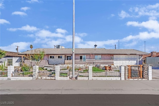 view of front of home with a garage, concrete driveway, a fenced front yard, and a tile roof