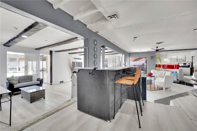 kitchen with open floor plan, a kitchen bar, and light wood-style floors