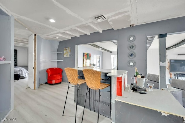 kitchen with a kitchen breakfast bar, visible vents, and light wood-style floors