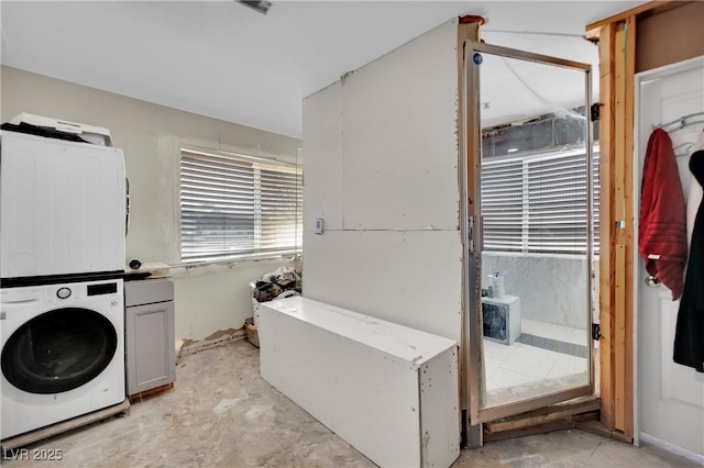 clothes washing area featuring cabinet space and stacked washer / drying machine