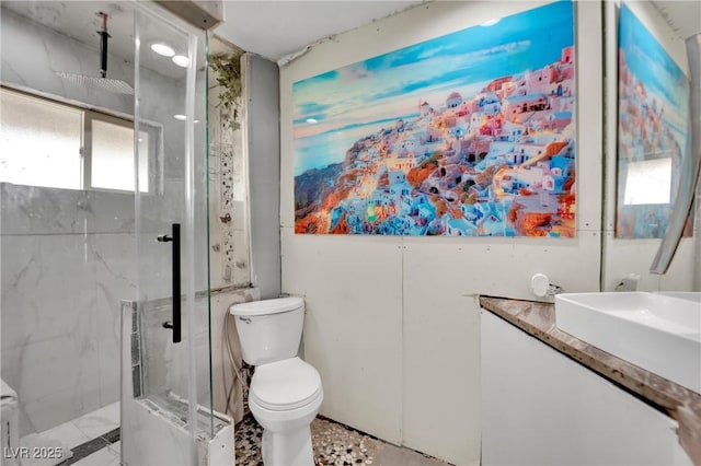 full bath featuring vanity, a marble finish shower, and toilet