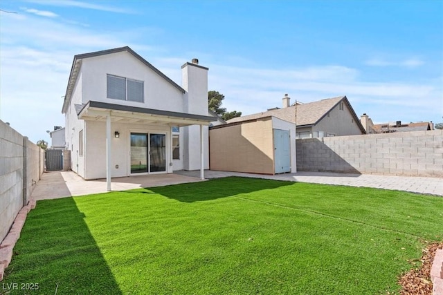 rear view of house with stucco siding, a lawn, a fenced backyard, an outbuilding, and a storage unit