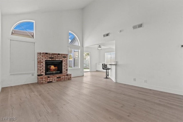 unfurnished living room with wood finished floors, a fireplace, visible vents, and baseboards