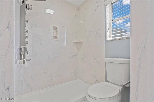 bathroom featuring a marble finish shower and toilet