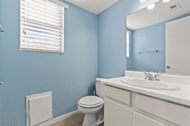 bathroom featuring visible vents, toilet, wood finished floors, baseboards, and vanity