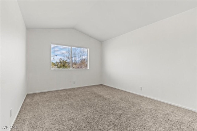 carpeted spare room with baseboards and lofted ceiling