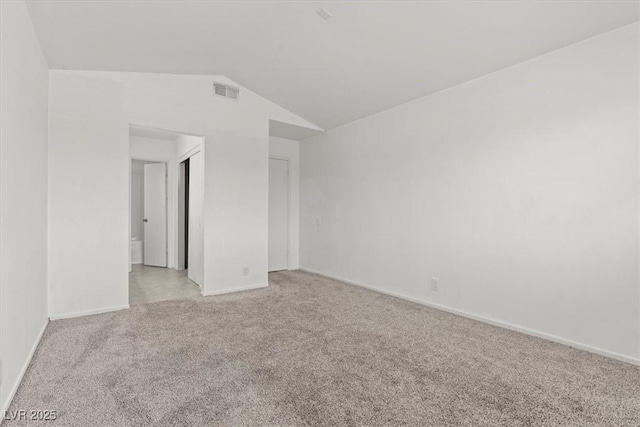 unfurnished room with lofted ceiling, light colored carpet, visible vents, and baseboards