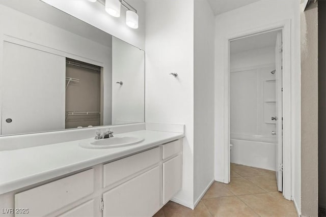 bathroom with tile patterned floors, a walk in closet, and vanity