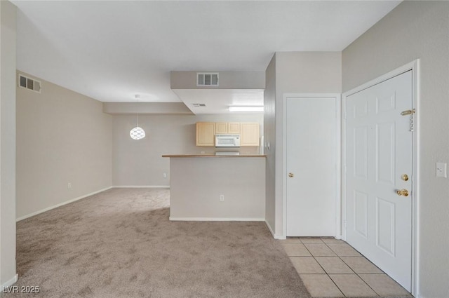 interior space with light tile patterned flooring, baseboards, visible vents, and light colored carpet