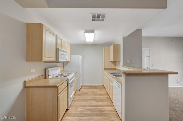 kitchen with white appliances, visible vents, a peninsula, light brown cabinetry, and light wood-style floors