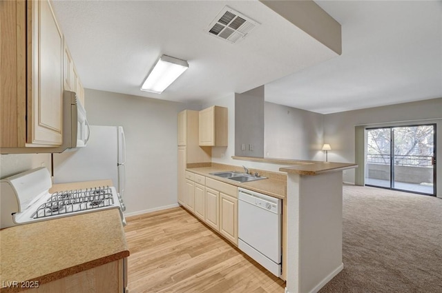 kitchen with white appliances, visible vents, open floor plan, a peninsula, and a sink