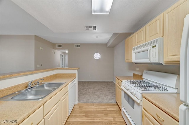 kitchen featuring white appliances, visible vents, decorative light fixtures, light countertops, and a sink