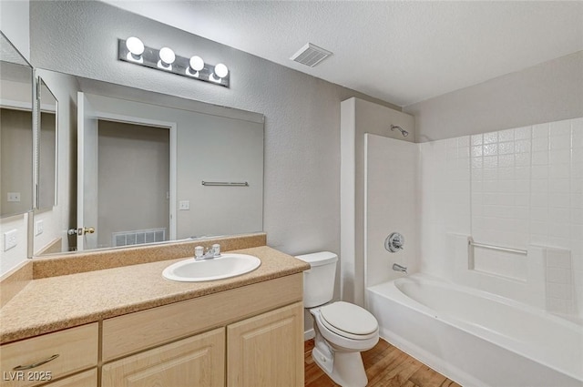 full bathroom featuring visible vents, toilet, wood finished floors, a textured ceiling, and shower / bathing tub combination